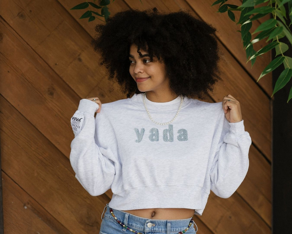 Model wearing a light gray Yada embroidered cropped sweatshirt.